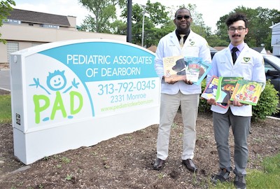 SNPhA President-Elect Obioma Opara and Kappa Psi Philanthropy Chair Jad Kawas display some of their book donations in front of Pediatric Associates of Dearborn.
