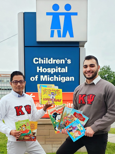 Kappa Psi brothers Joseph Paul Javier and Hussein Safaoui at the DMC Children’s Hospital, one of Reach Out and Read’s local sites.
